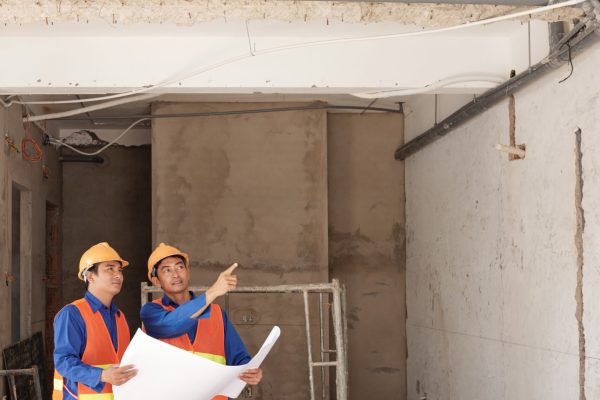 Asian construction engineers discussing pipe assembling in building